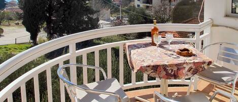 A balcony with a table and chairs, a bottle, and glasses.