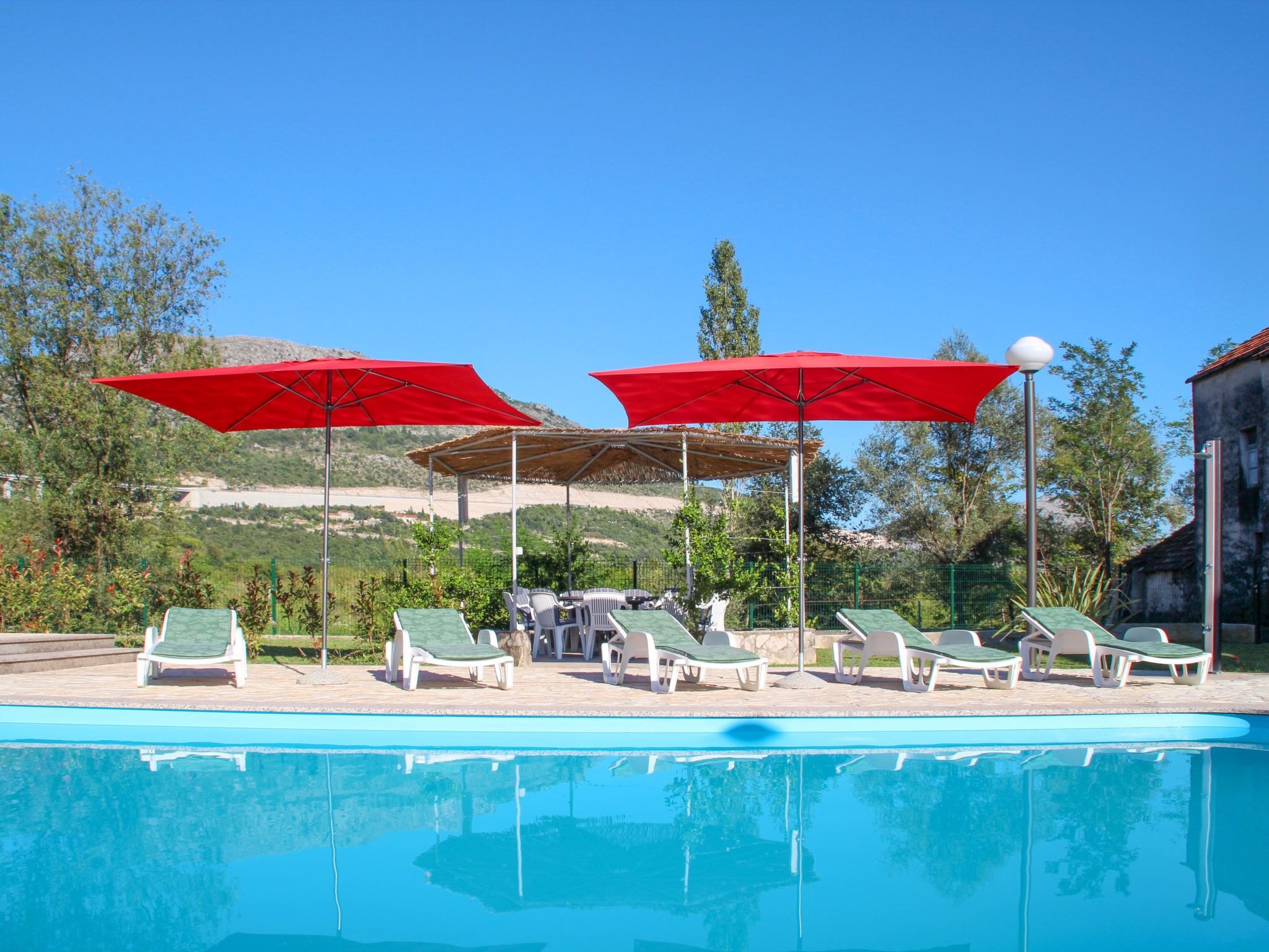 A pool area with lounge chairs and red umbrellas.