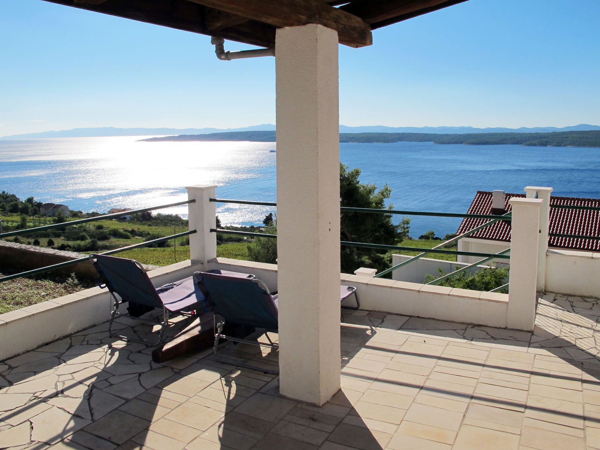 Une terrasse avec deux fauteuils et une table, d’où l’on peut admirer un plan d’eau et des montagnes au loin.