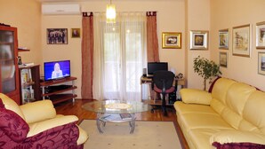 A living room with a yellow sofa, a glass coffee table, a TV, a computer desk, and a bookshelf. - Apartment Mira by Interhome (Brač/Splitska)