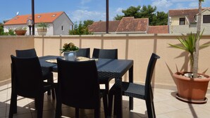An outdoor patio with a table and chairs, potted plants, and a view of neighboring houses. - Apartment Mira by Interhome (Brač/Splitska)