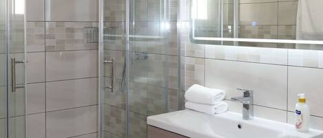 Une salle de bain moderne avec une douche à parois de verre, un meuble-lavabo et un grand miroir.
