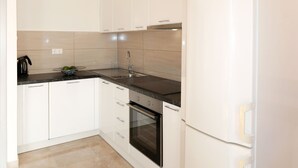Eine moderne Küche mit weißen Schränken, einer schwarzen Arbeitsplatte, einer Edelstahl-Spüle und einem eingebauten Backofen.
