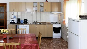 A compact kitchen with a dining table, chairs, a stove, a sink, and cabinets. - Villa Saba by Interhome (Trogir)