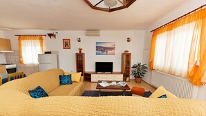 A cozy living room with a large sofa, a TV, and a dining table. There is a kitchen area with a stove and cabinets. - Villa Saba by Interhome (Trogir)
