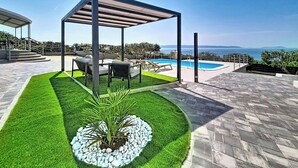 A rooftop pool area with a pergola, seating, and a view of the sea.