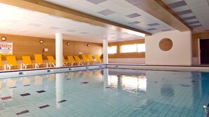An indoor swimming pool with tiled walls and ceiling, wooden beams, and yellow lounge chairs along the poolside. - Parc des Airelles by Interhome (Les Orres)