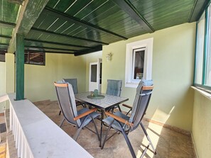 Un patio techado con mesa y sillas, un banco y una ventana con vistas.