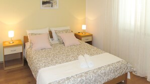 A neatly made bed with a patterned bedspread, two bedside tables with lamps, and a picture on the wall. - Apartment Toni by Interhome (Šibenik)