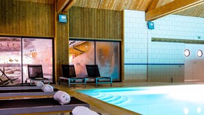 Ein Wellnessbereich mit Pool, Holzwänden und Liegestühlen.