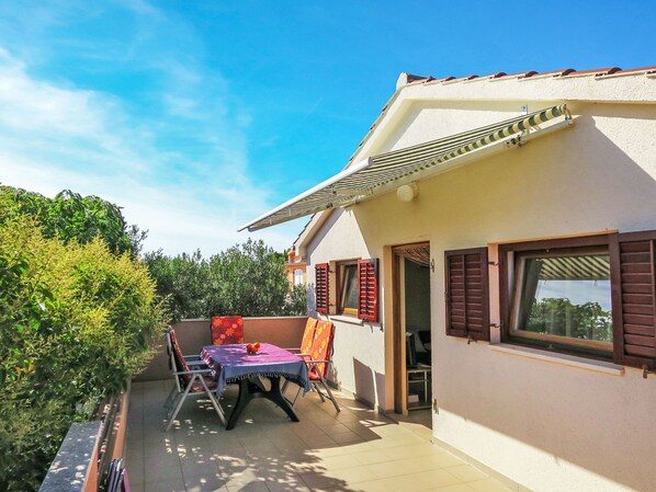 A house with a patio, a table with a tablecloth, and a window with shutters.