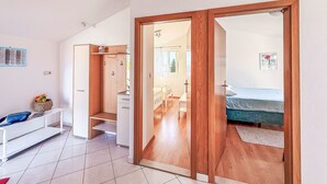 A room with a bed, a wooden wardrobe, a desk with a chair, and a small table with a basket of flowers. - Apartment Ana by Interhome (Biograd na Moru)