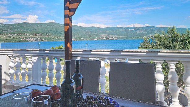 A balcony with a table set for dining, overlooking a scenic view of a body of water and hills. - Valentina by Interhome (Zadar)