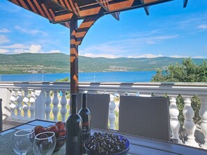 A balcony with a table set for dining, overlooking a scenic view of a body of water and hills. - Valentina by Interhome (Zadar)