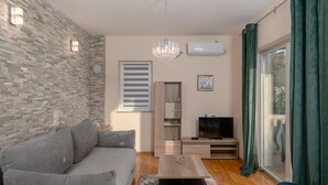 Un salon moderne avec un canapé gris, une table basse en bois, un téléviseur et un rideau vert.