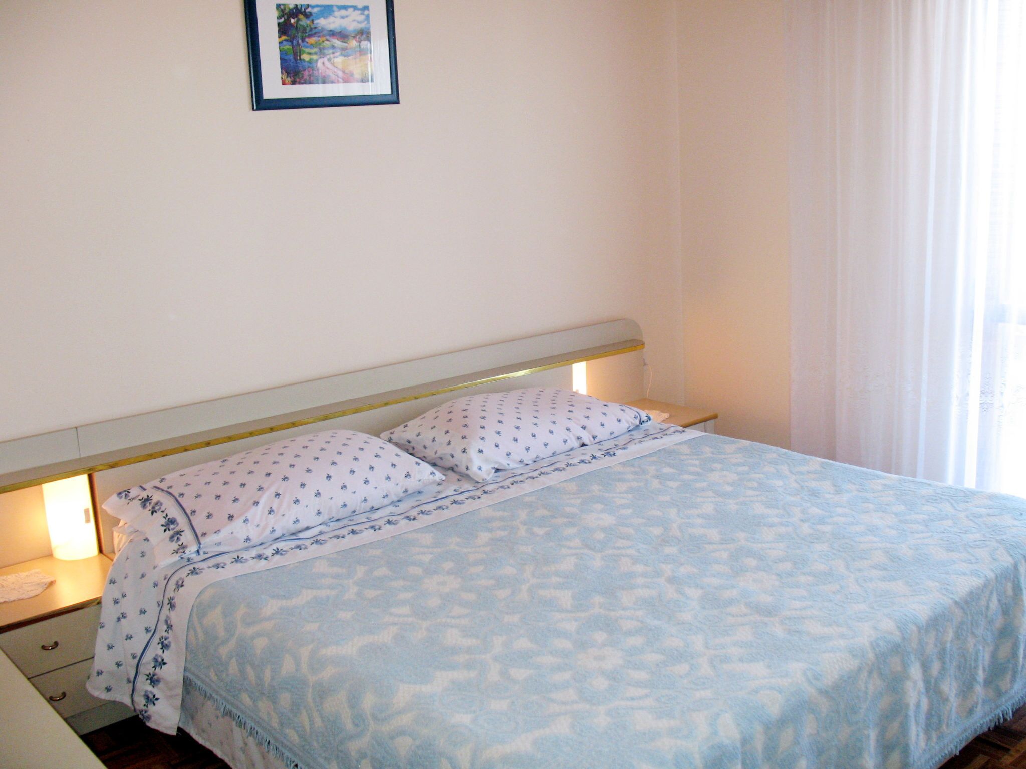 A bed with a patterned bedspread, a headboard, and bedside lamps.