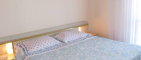A bed with a patterned bedspread, a headboard, and bedside lamps.