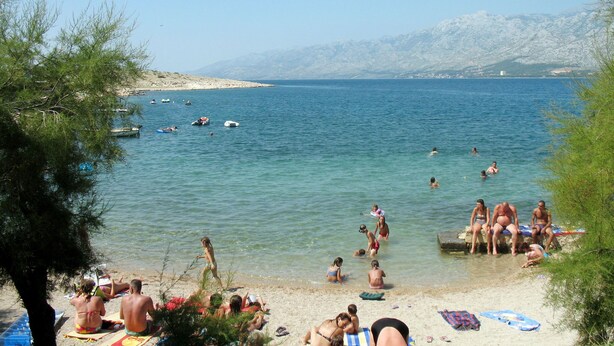 A beach with people sunbathing and swimming, boats in the water, and mountains in the background. - Apartment Lukeni by Interhome (Vinjerac)