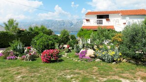 A white building with a red-tiled roof, surrounded by a variety of colorful flowers and greenery. - Apartment Lukeni by Interhome (Vinjerac)