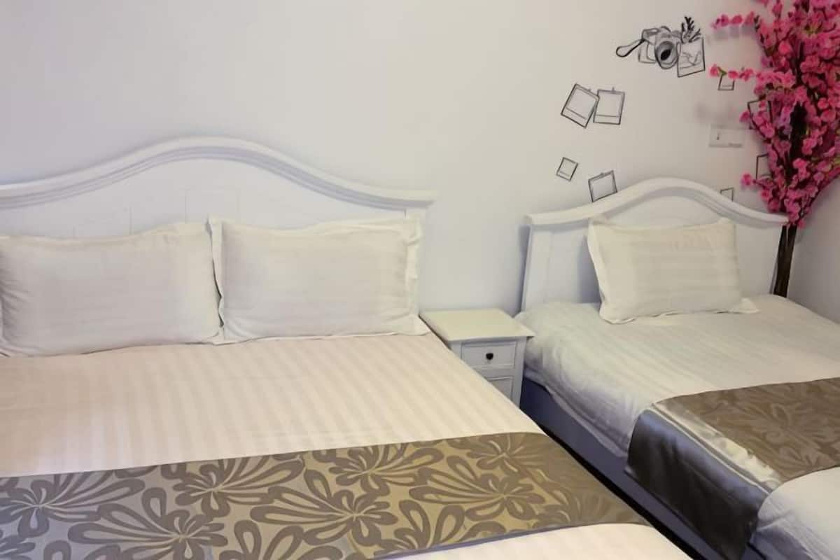 A double bed with a patterned bedspread, a nightstand, and a wall with a decorative item.