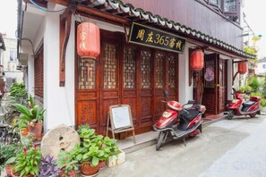 A traditional building with a signboard, potted plants, and scooters parked outside. - 365 Boutique Inn (Kunshan)