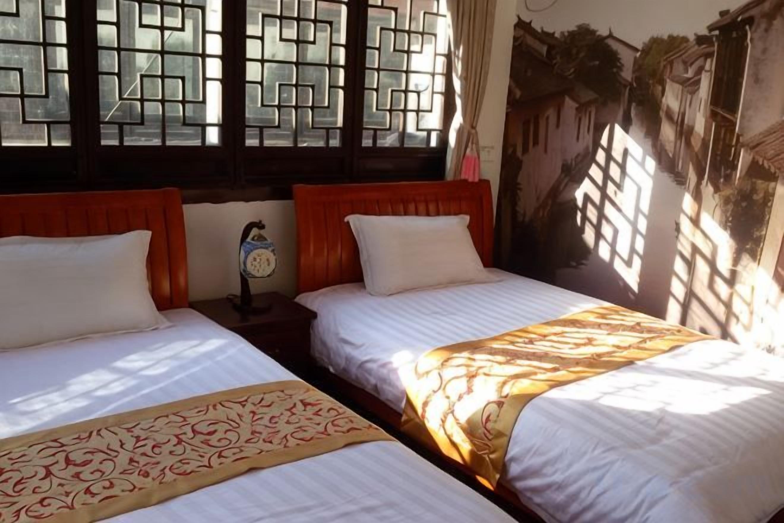 Une chambre avec deux lits, des têtes de lit en bois et un modèle de fenêtre traditionnel.