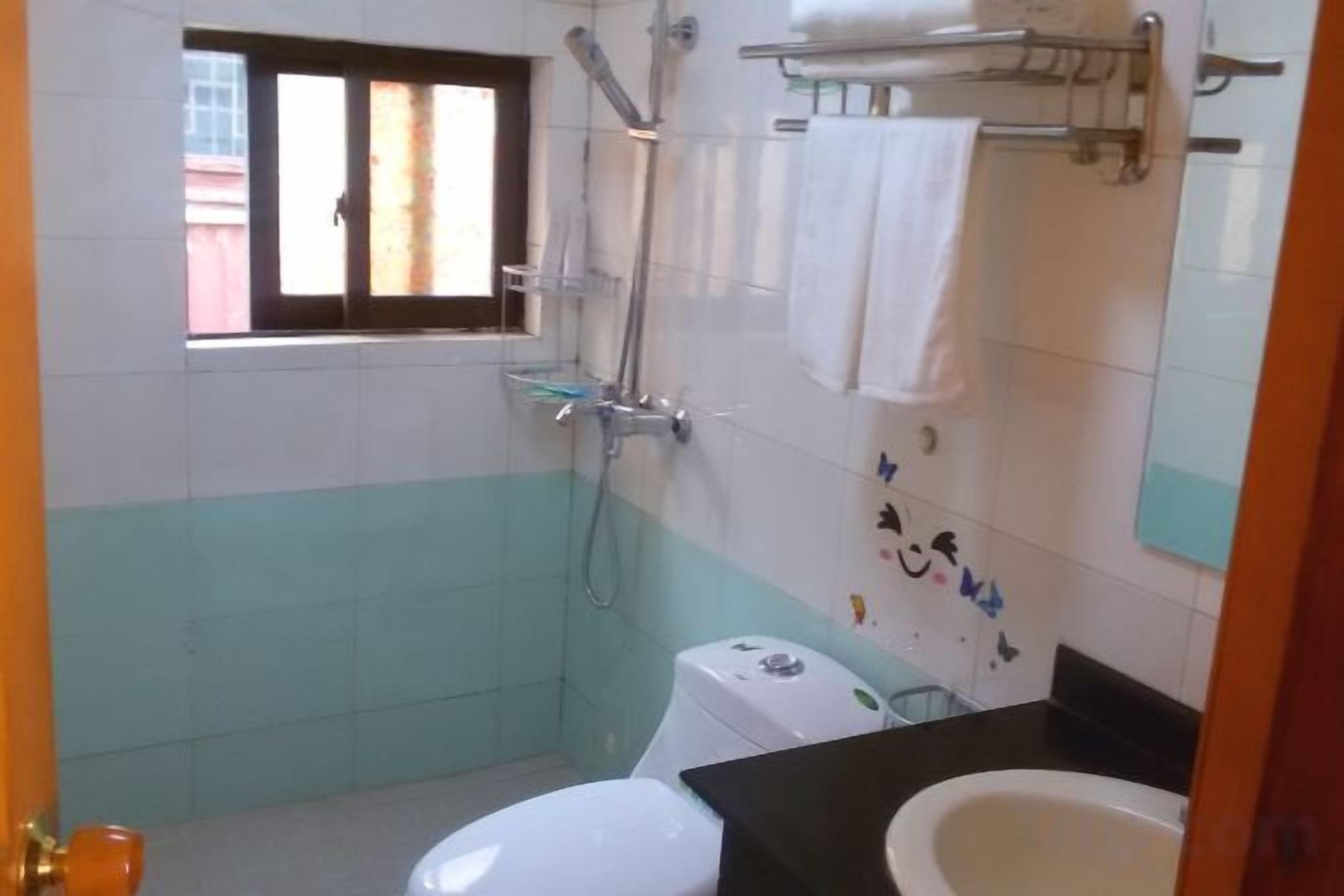 Een badkamer met toilet, wastafel, douche en een raam.