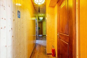 A wooden hallway with a fire extinguisher, a door, and a sign on the wall. - 365 Boutique Inn (Kunshan)