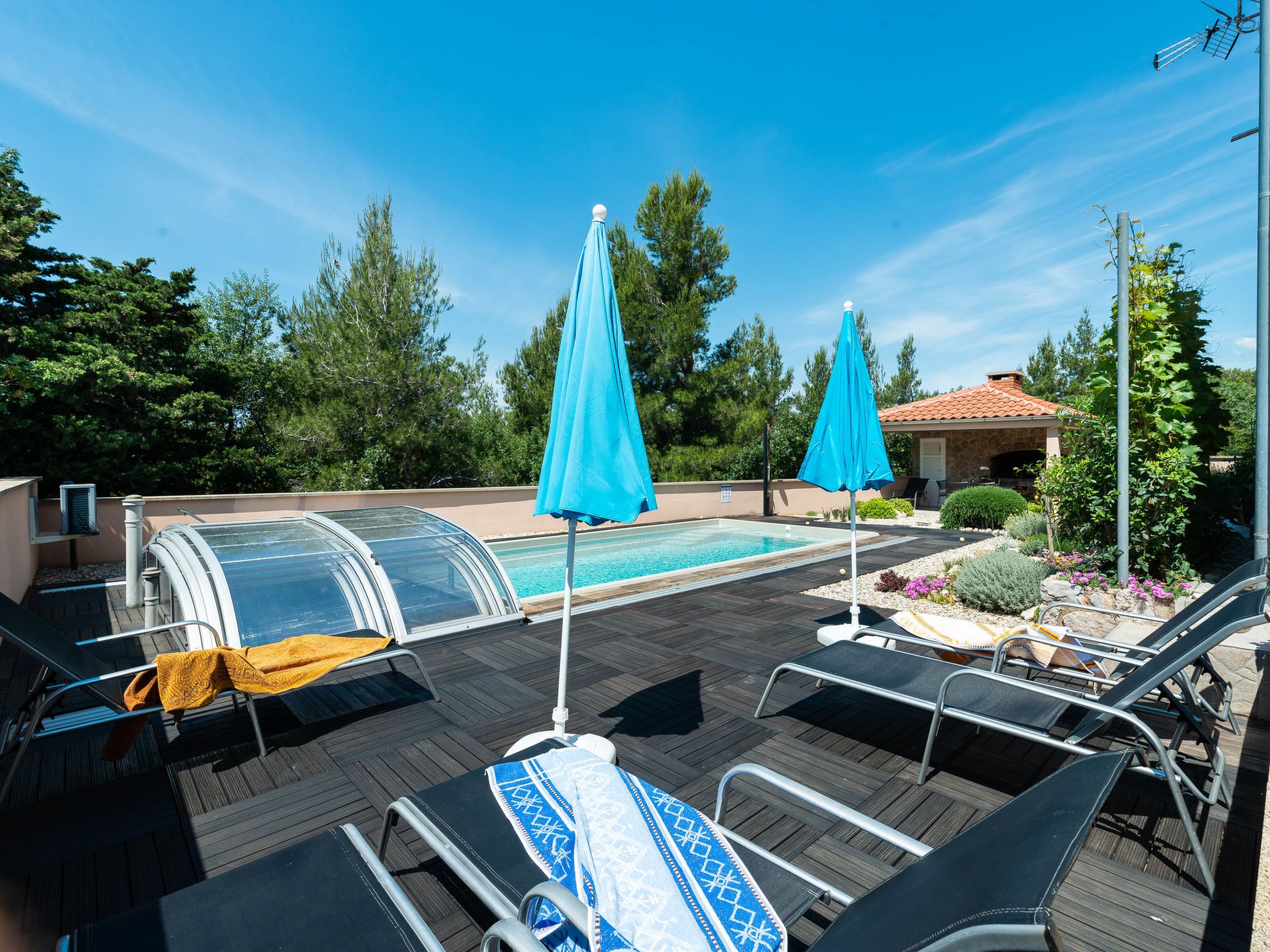 Ein Poolbereich mit Liegestühlen, einem Pool mit Glasveranda und einem Gebäude mit Ziegeldach im Hintergrund.