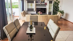 Un salon moderne avec un canapé, une table à manger avec des verres à vin, un téléviseur et une cheminée.
