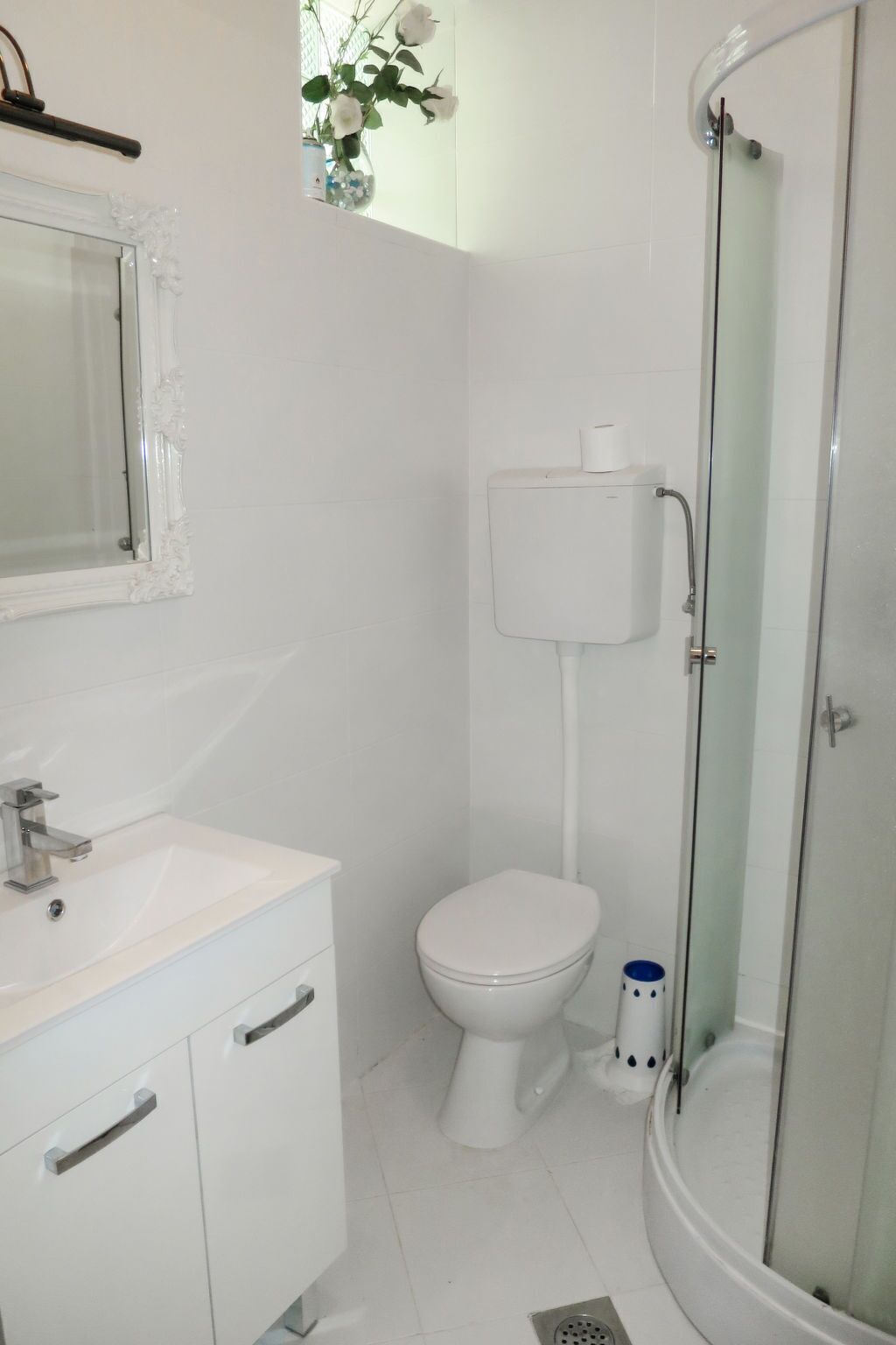 Un baño moderno con lavamanos, inodoro y ducha blancos.