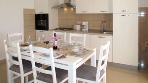 Eine moderne Küche mit weißen Schränken, einem Gasherd, einer Kaffeemaschine und einem Kühlschrank.