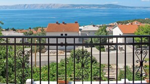 A balcony with a view of a coastal town, houses with red-tiled roofs, and a clear blue sea. - Valentina by Interhome (Novi Vinodolski)