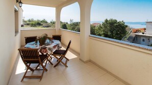 Een balkon met een tafel en stoelen, met uitzicht op een schilderachtig zeegezicht en groen.