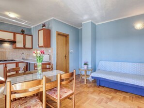 Ett kompakt bostadsutrymme med en matplats, ett litet kök och en soffa.