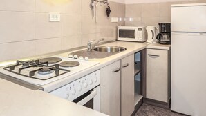 Une cuisine compacte équipée d’une cuisinière à gaz, d’un four à micro-ondes, d’une machine à café et d’un réfrigérateur.