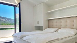 Een slaapkamer met een bed, een kledingkast en uitzicht op het omliggende landschap.