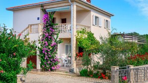 A two-story house with a balcony, surrounded by lush greenery and flowering plants. - Andjelka by Interhome (Krk/Krk)