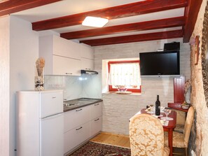 Compact kitchen with oven, microwave, and flat-screen TV.