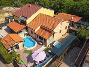A multi-story house with a swimming pool, outdoor seating, and a covered patio area.