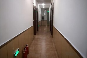 A corridor with doors on both sides, fire extinguishers, and emergency exit signs. - Foshan Meek Hotel (Flatland Cloth Market Cowboy City) (Foshan)