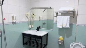 Ένα μπάνιο με νιπτήρα, καθρέφτη, κρεμάστρα για πετσέτες και τουαλέτα.