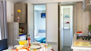 Habitación de hotel compacta con comedor, kitchenette y una cama.