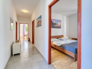 A bedroom with a wooden bed, a nightstand, and a view of a garden through an open door.