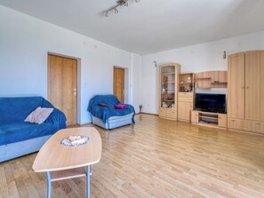 Amplia sala de estar con un sofá, un sillón más pequeño, un mueble para televisión y un armario de madera.