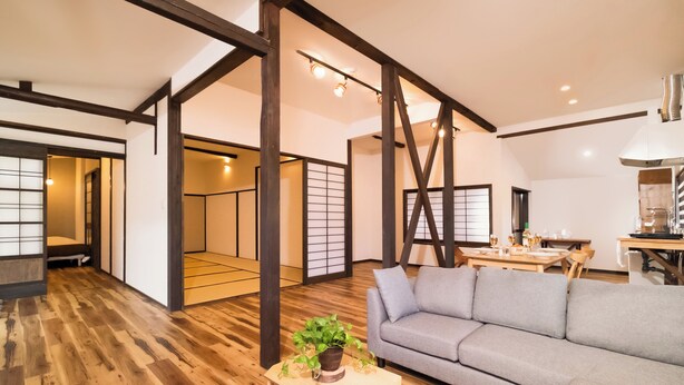 Un vaste espace de vie doté d’un plancher en bois, d’un canapé gris et d’une table à manger avec des chaises.