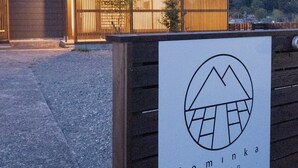 Un bâtiment sur lequel on peut lire l’inscription « Cominka Yufutsu » et qui arbore un logo représentant une montagne et une maison.