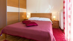 Ein Schlafzimmer mit einem Bett, zwei Nachttischen, einem Holzschrank und einer Heizung.