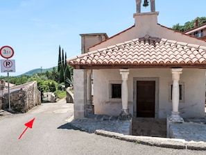 A small building with a tiled roof and columns, a bell on top, and a no parking sign nearby. - Apartment Branka by Interhome (Mošćenička Draga)