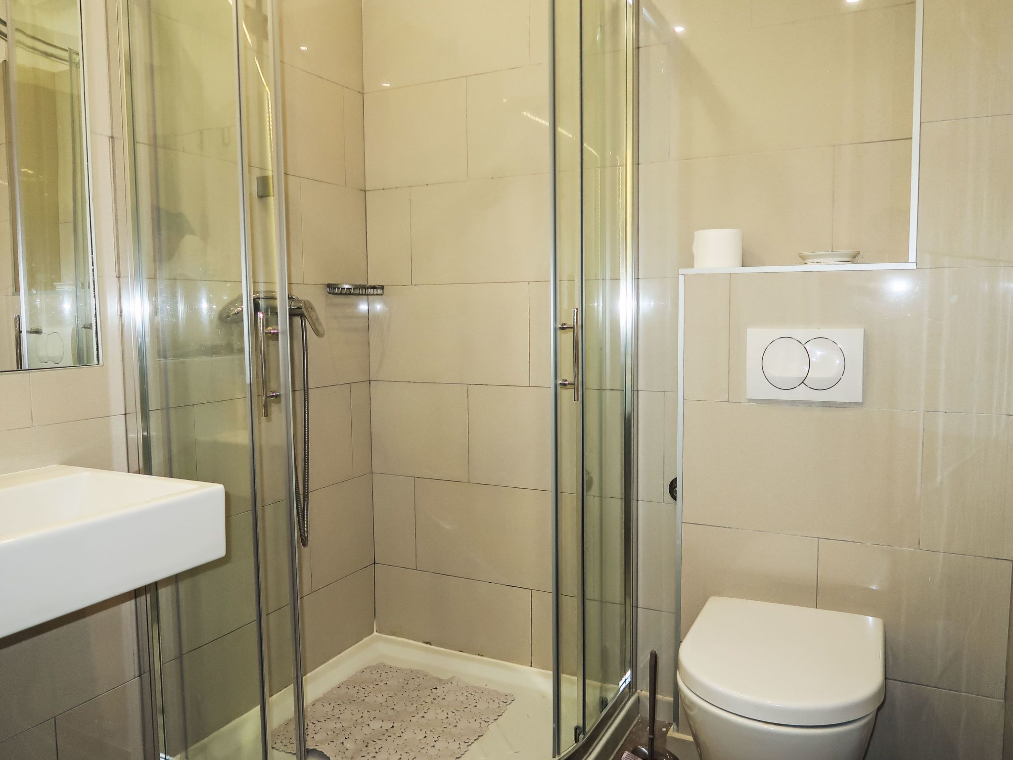 A bathroom with a glass-enclosed shower, a toilet, and a sink.